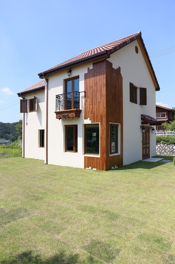 Tradycyjny dom z ciepłą białą elewacją, brązowym dachem i brązowymi oknami. Biała elewacja z brązowym dachem.